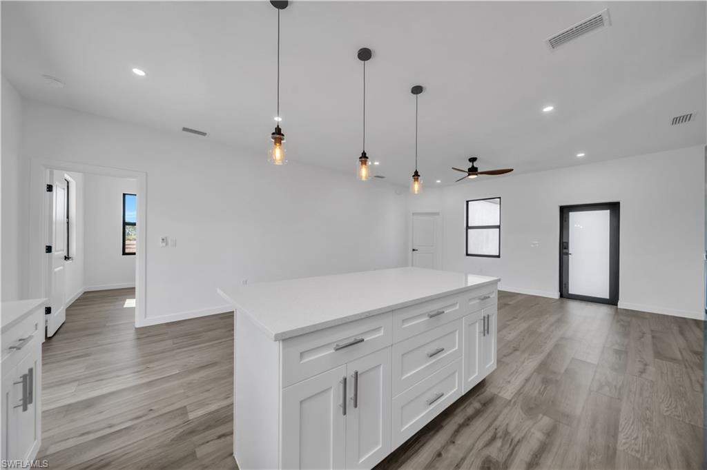 Central kitchen island with white cabinetry and a light-toned countertop, complemented by pendant lighting