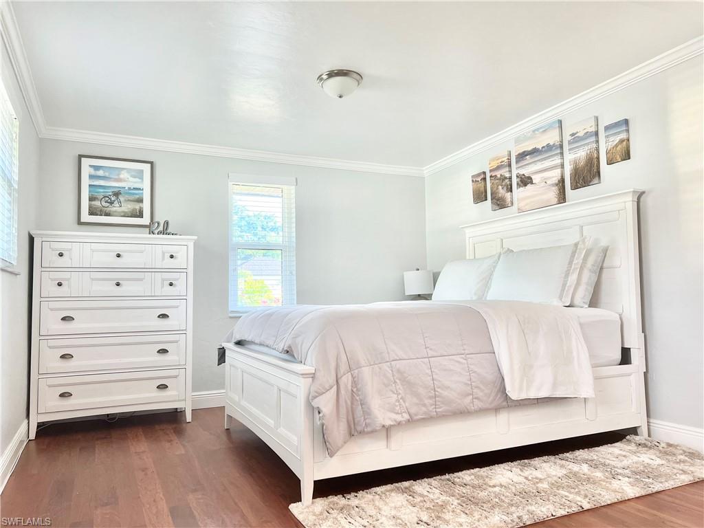 Wood-finish flooring, crown molding, and two windows with blinds