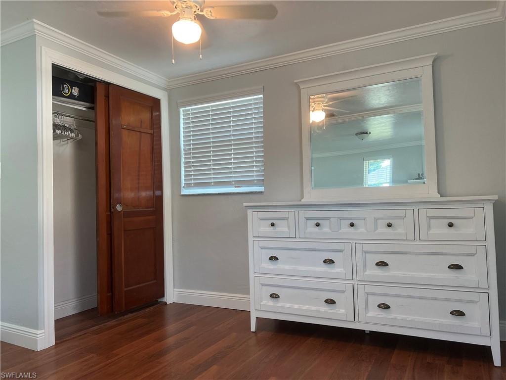 Wood-finish flooring, crown molding, a built-in ceiling fan with light, and a window with blinds