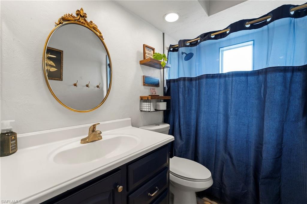 Vanity with dark cabinetry and gold-tone hardware, oval undermount sink with gold-tone faucet, and an ornate gold-framed mirror
