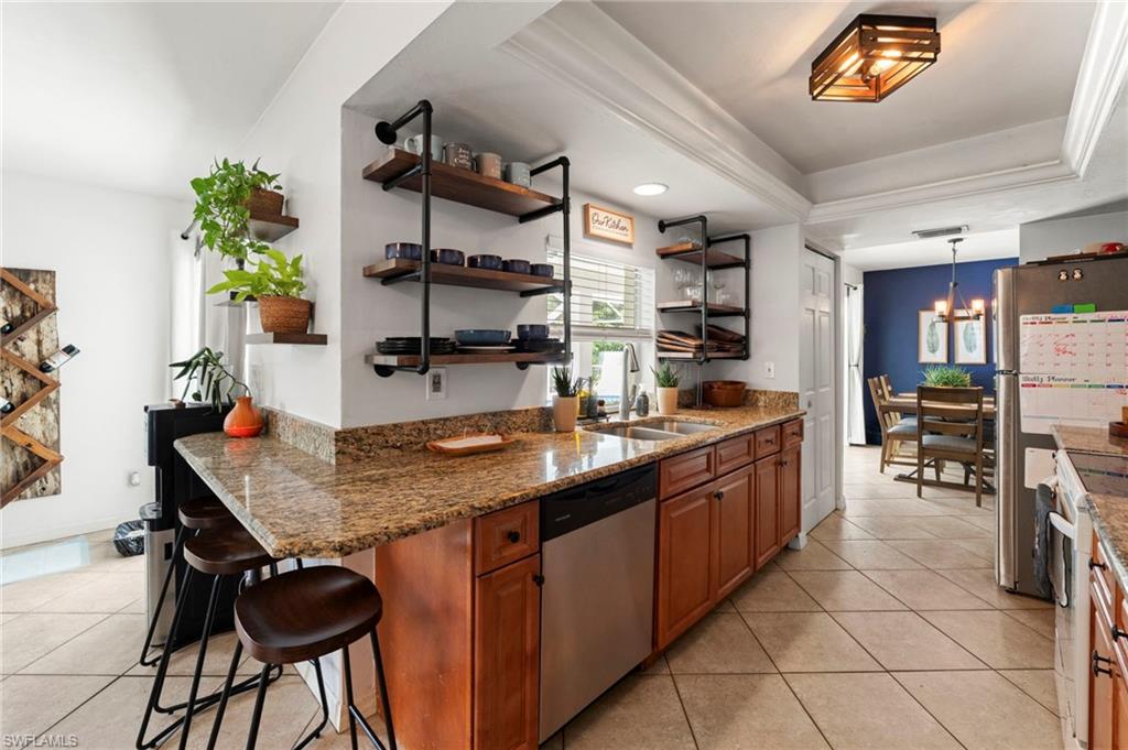 Kitchen featuring granite countertops, wood cabinetry, stainless steel dishwasher, tile flooring, and open shelving