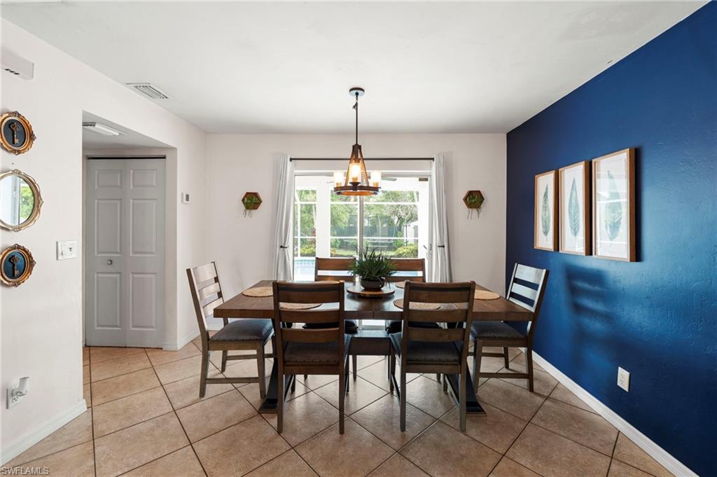 Elegant dining room showcasing a rich blue accent wall, tile flooring, and abundant natural light from large windows