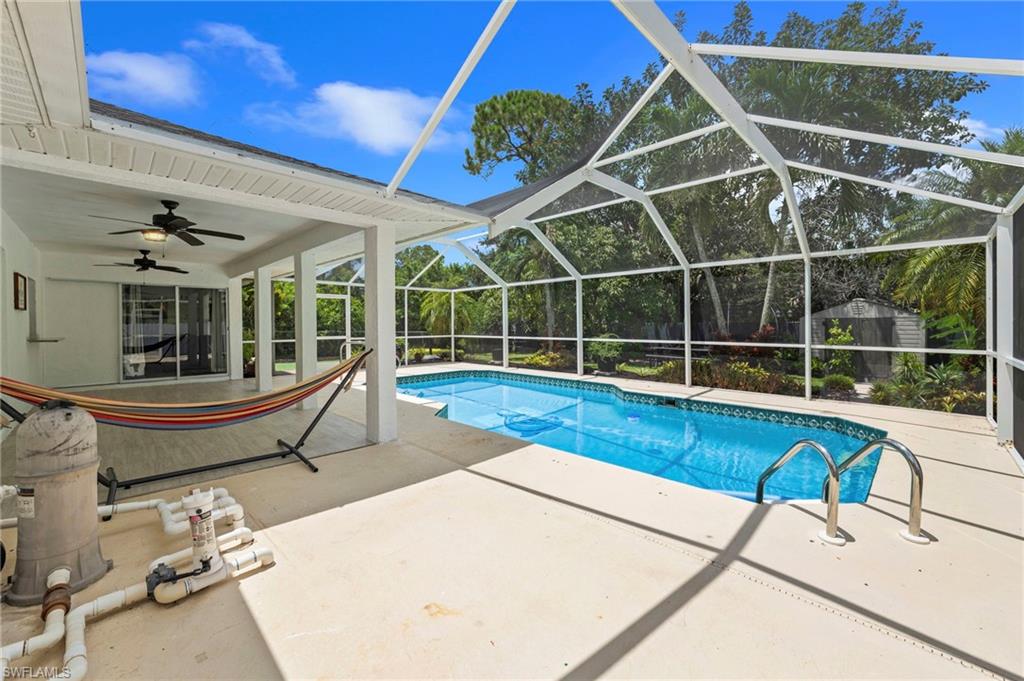 Screened pool enclosure with a rectangular swimming pool, concrete deck, covered patio, and dual ceiling fans