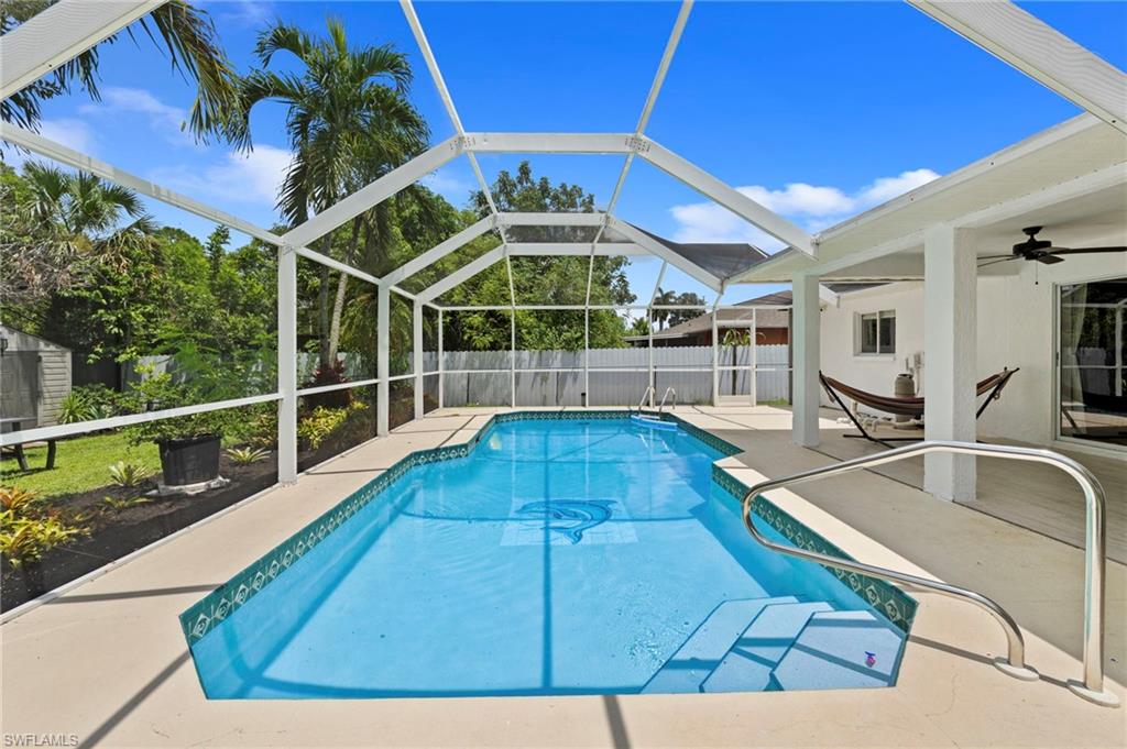 Screened swimming pool with integrated steps, surrounded by a concrete deck and a covered patio area with a ceiling fan