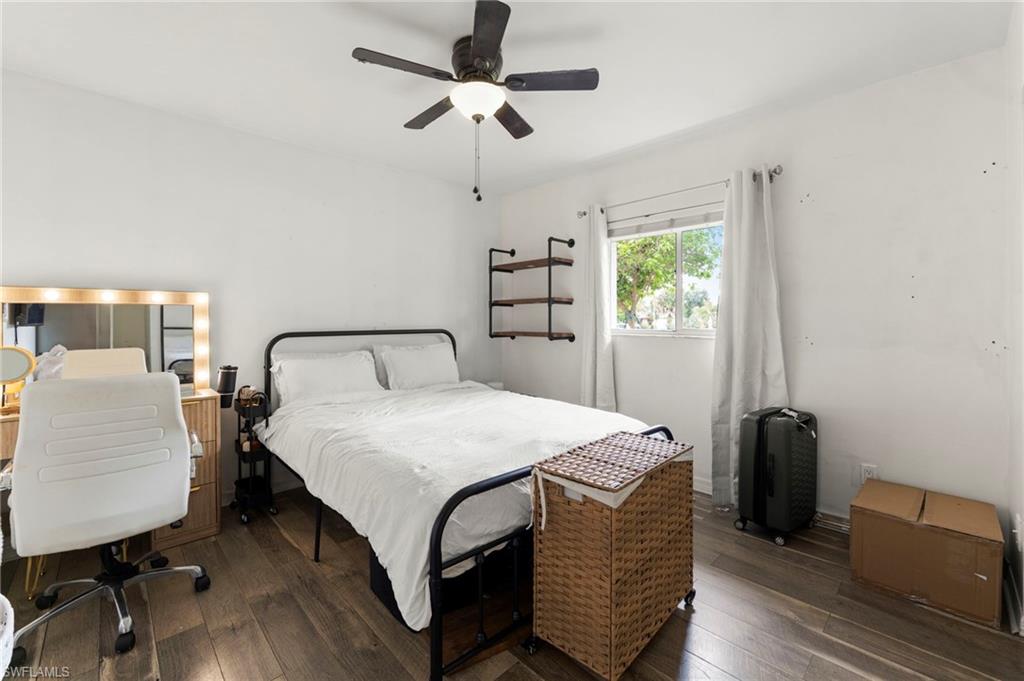 Wood-finish flooring, ceiling fan with integrated lighting, wall-mounted shelving, and a window with natural light
