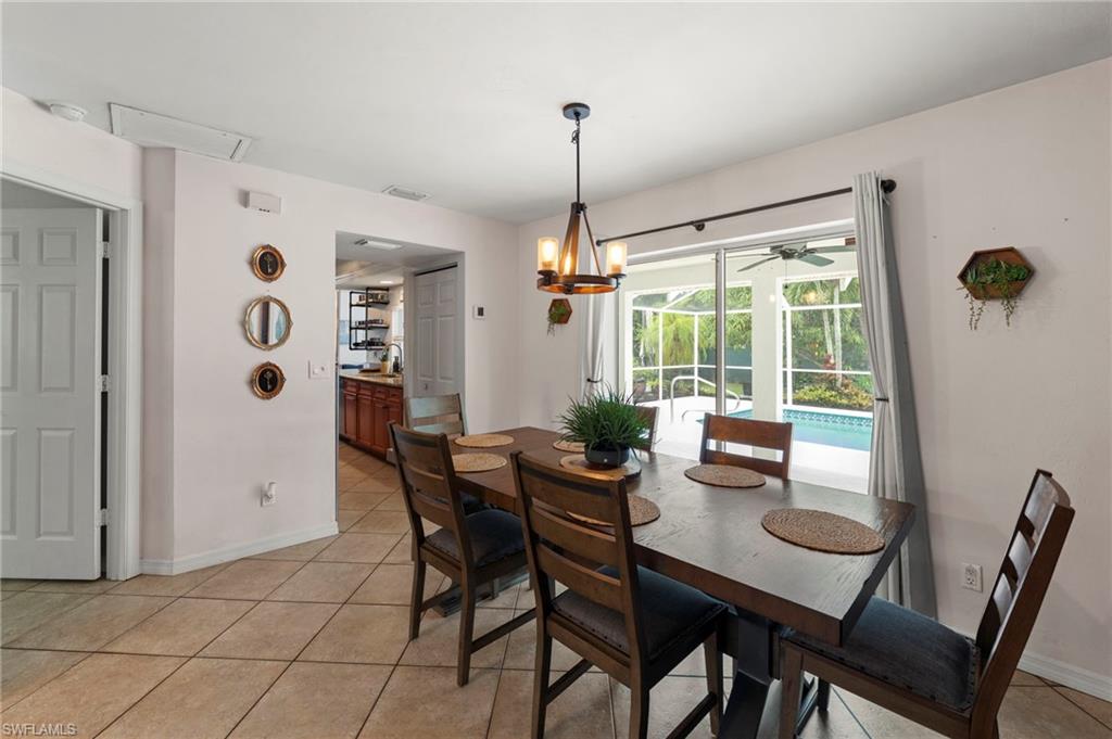Tiled flooring extending throughout, contemporary chandelier, sliding glass doors to outdoor area, and a pass-through opening to the kitchen