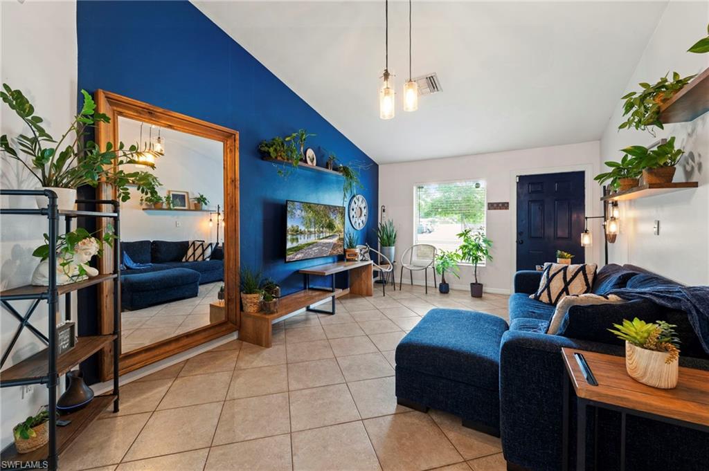 Bright, open living space showcasing a striking cobalt accent wall, tile flooring, and abundant natural light from multiple windows
