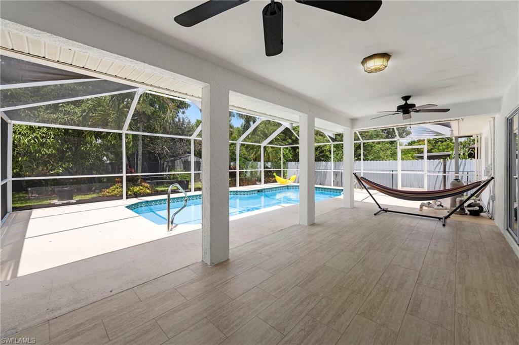Expansive screened lanai with wood-finish flooring, multiple ceiling fans, and recessed lighting overlooking a resort-style swimming pool
