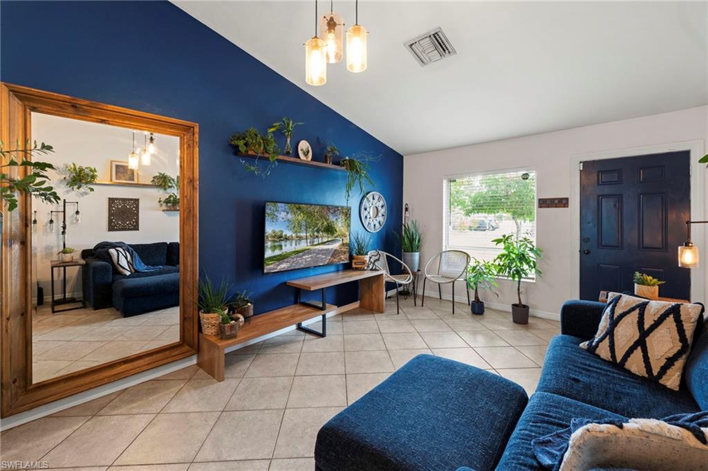 Smooth tile flooring, blue accent wall with shelving, recessed lighting, and a dark paneled entry door
