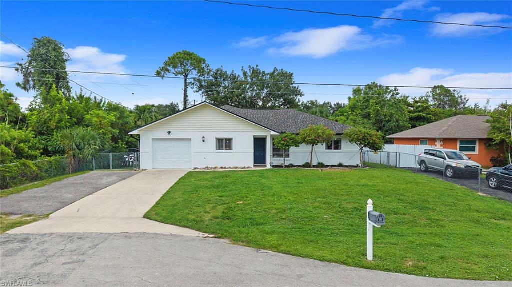Charming single-story residence featuring a spacious front-facing garage, freshly manicured lawn with mature landscaping, and a long driveway with ample parking