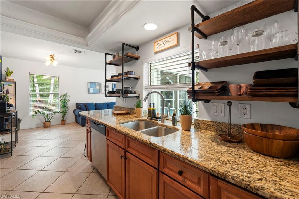 Kitchen featuring a double basin stainless steel sink, granite countertops, wood cabinetry, and open shelving