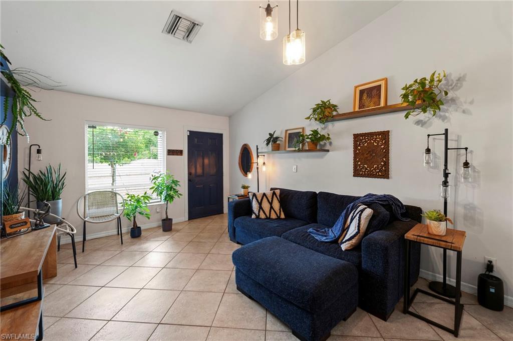 Vaulted ceiling, recessed lighting, tile flooring, window with blinds, dark-paneled door