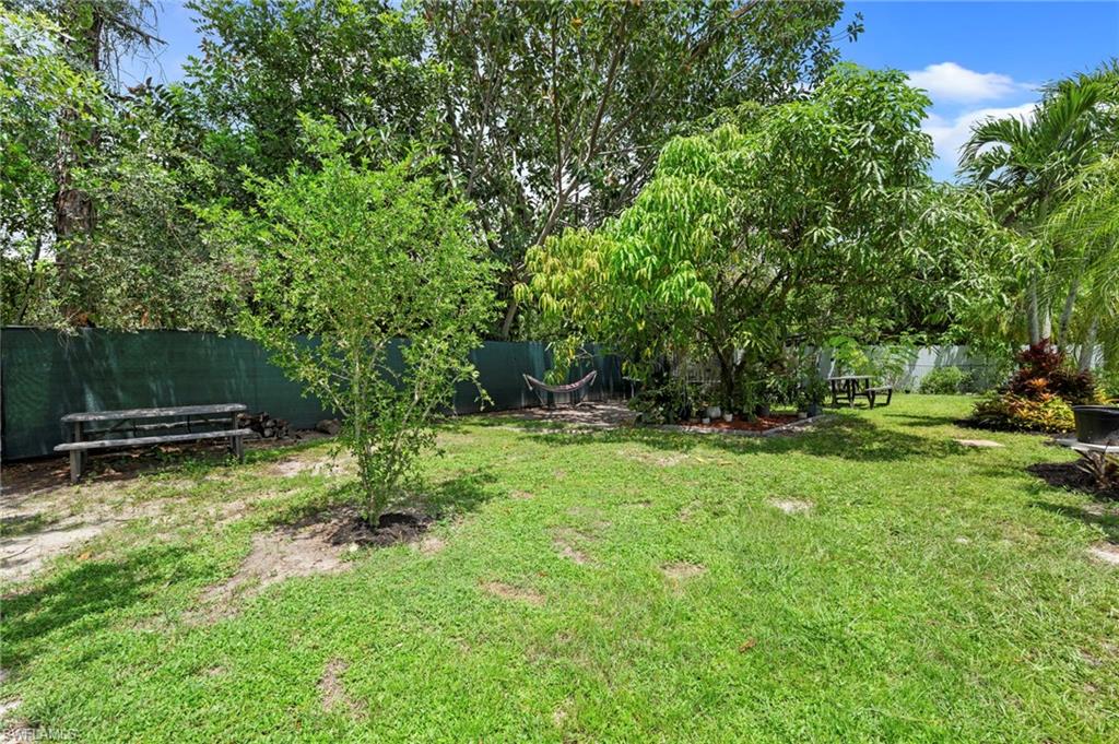 Expansive grassy yard area with mature trees and a privacy fence