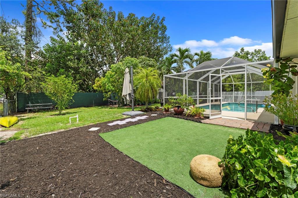 Screened-in swimming pool and patio area, artificial turf section, and natural grass lawn with mature landscaping