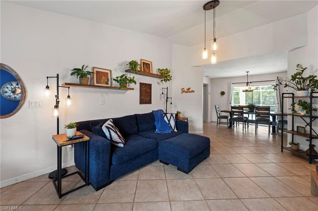 Open-concept living area featuring a tile-finish floor, pendant lighting, and built-in wall shelving with decorative planting ledges
