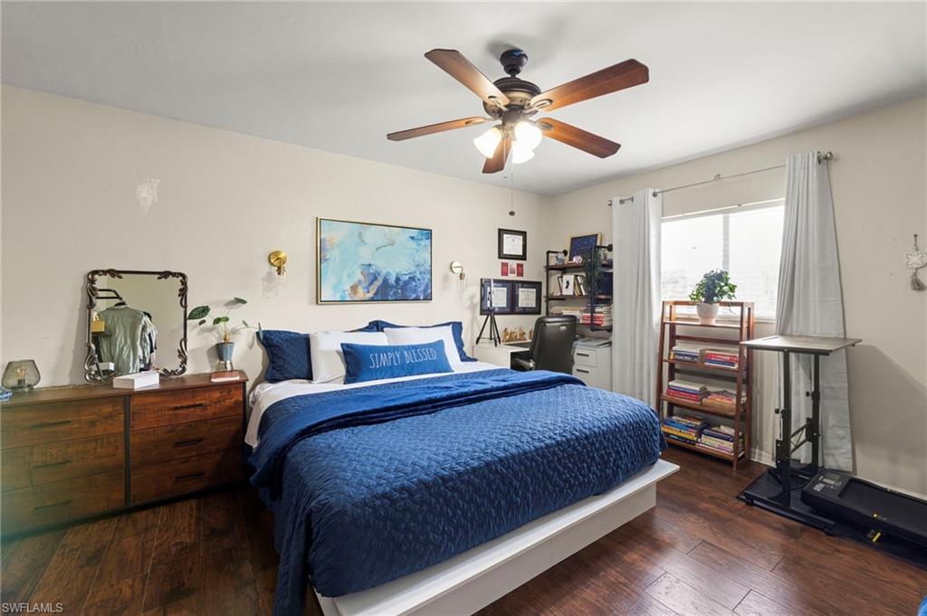 Spacious room featuring wood-finish flooring, a ceiling fan with integrated lighting, and a double window