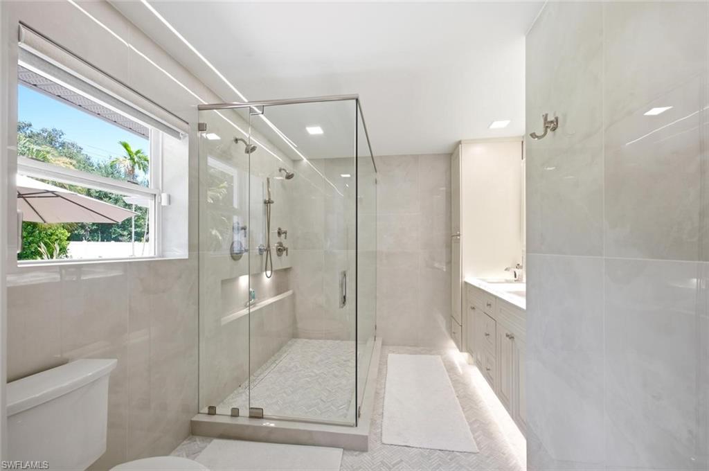 Primary Bathroom/Stone tile flooring, dual head walk-in shower, and double vanity