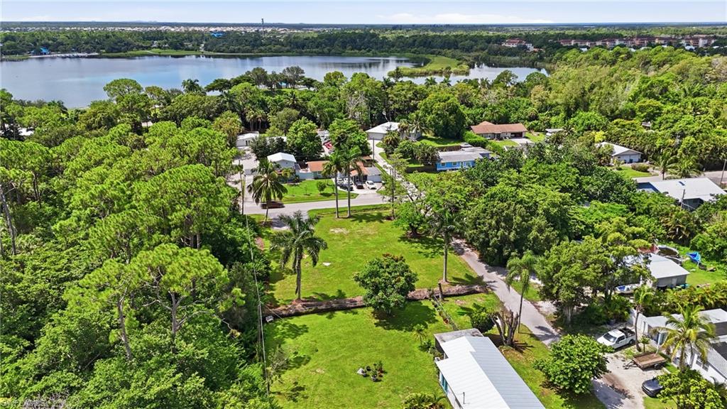 Expansive lot featuring a green lawn, mature trees, and a distant body of water