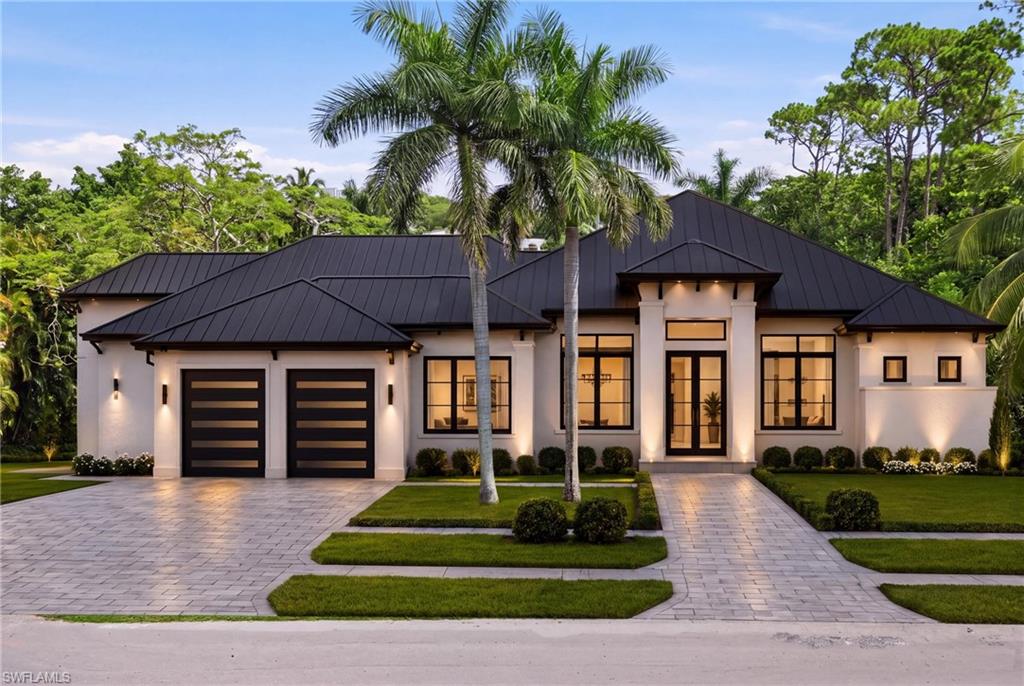Modern architectural design with a dark metal roof, stucco exterior, and black-framed windows
