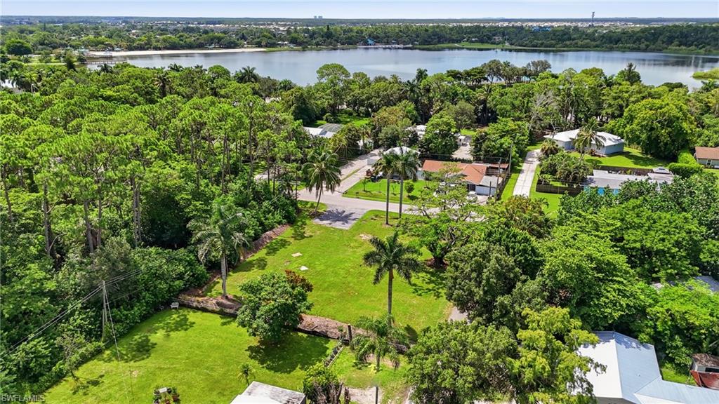 Expansive green lot with established foliage, surrounded by a lake and dense tree cover