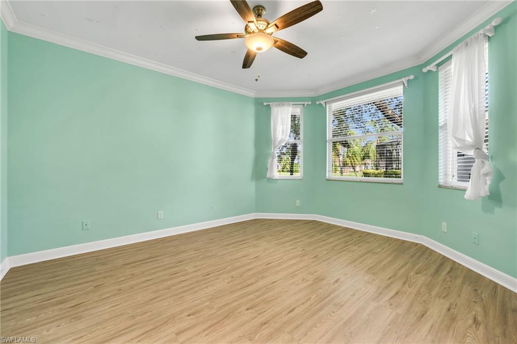 Wood-finish flooring, ceiling fan, multiple windows with blinds, and crown molding