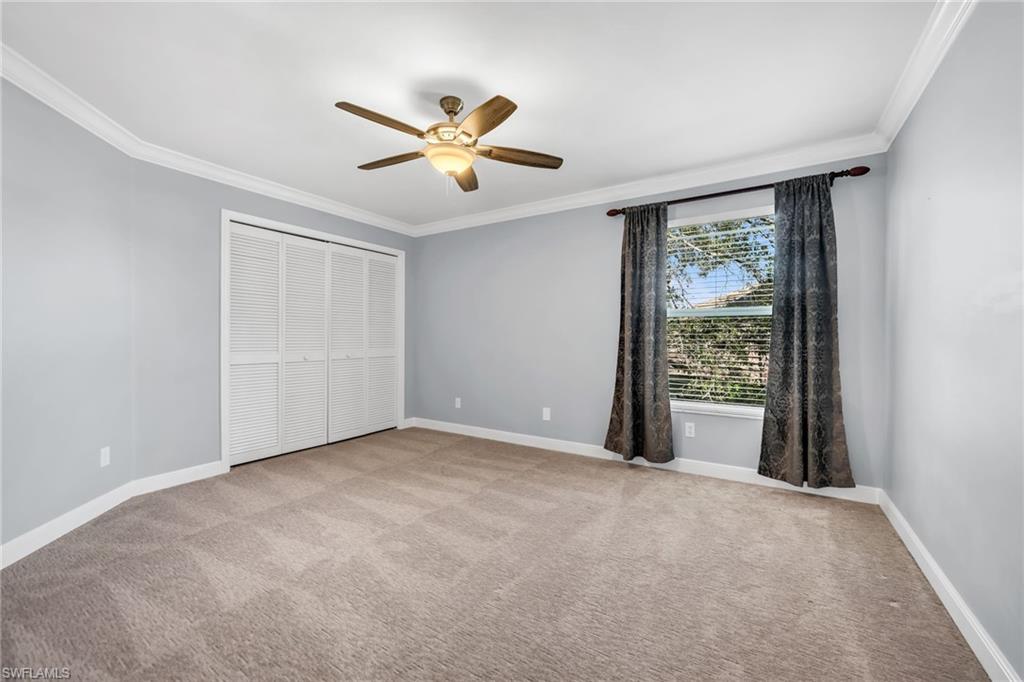 Recessed window with blinds, ceiling fan with integrated lighting, louvered closet doors, and crown molding