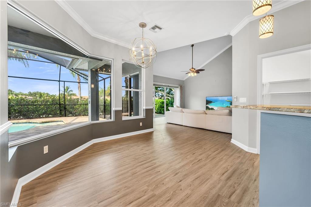 Wood-finish flooring, vaulted ceilings, and a decorative chandelier