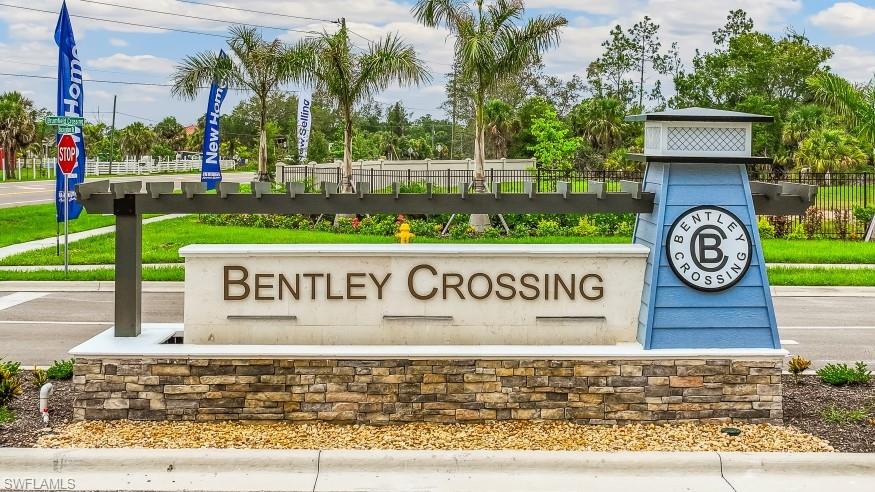 The property features a prominent entrance sign with stone detailing and a distinctive blue architectural element, set against a backdrop of lush green landscaping and palm trees