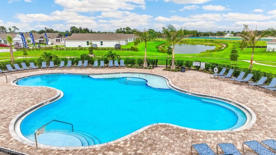 The property features a large outdoor swimming pool with a paved deck area, surrounded by lounge chairs, and palm trees