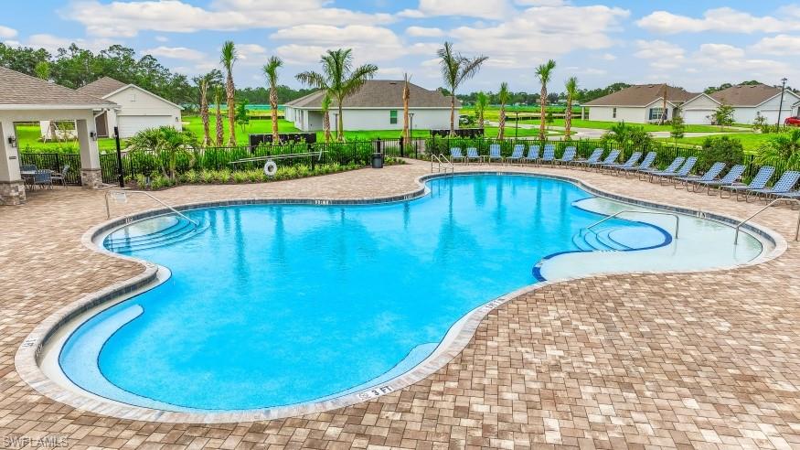 The community features a large swimming pool with an integrated spa, surrounded by a paver deck and several lounge chairs