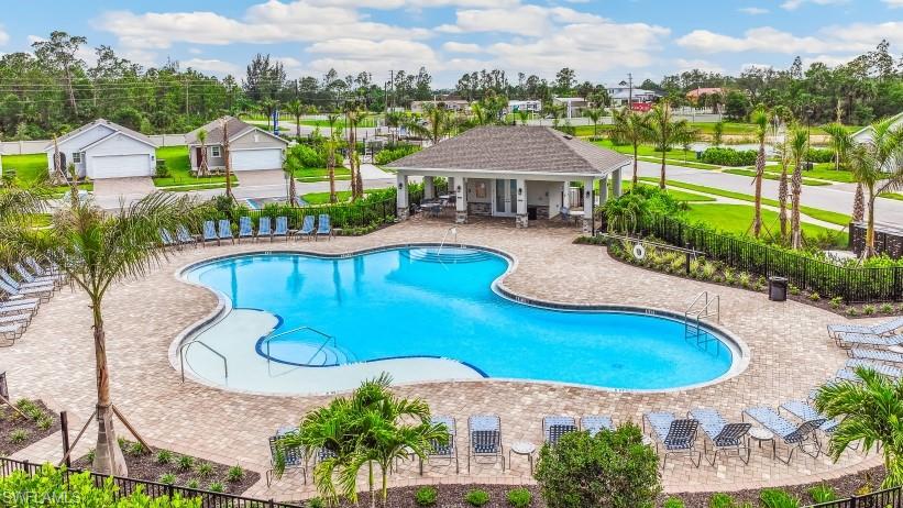 The community features a large, irregularly shaped swimming pool surrounded by a paved deck area with numerous lounge chairs