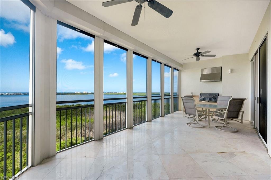 Expansive balcony featuring large format tile flooring, black metal balcony railing, and multiple ceiling fans