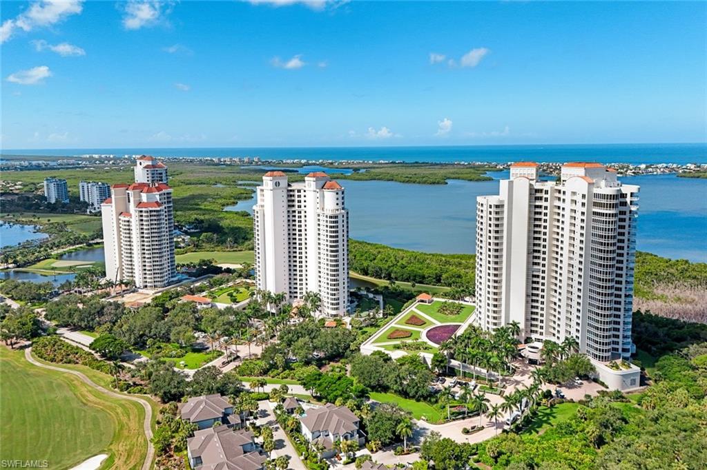 Waterfront high-rise residences featuring modern tower architecture with floor-to-ceiling windows, manicured landscaping with mature trees and expansive green spaces, direct water access, and panoramic vistas of the coastal waterway and surrounding preserve lands