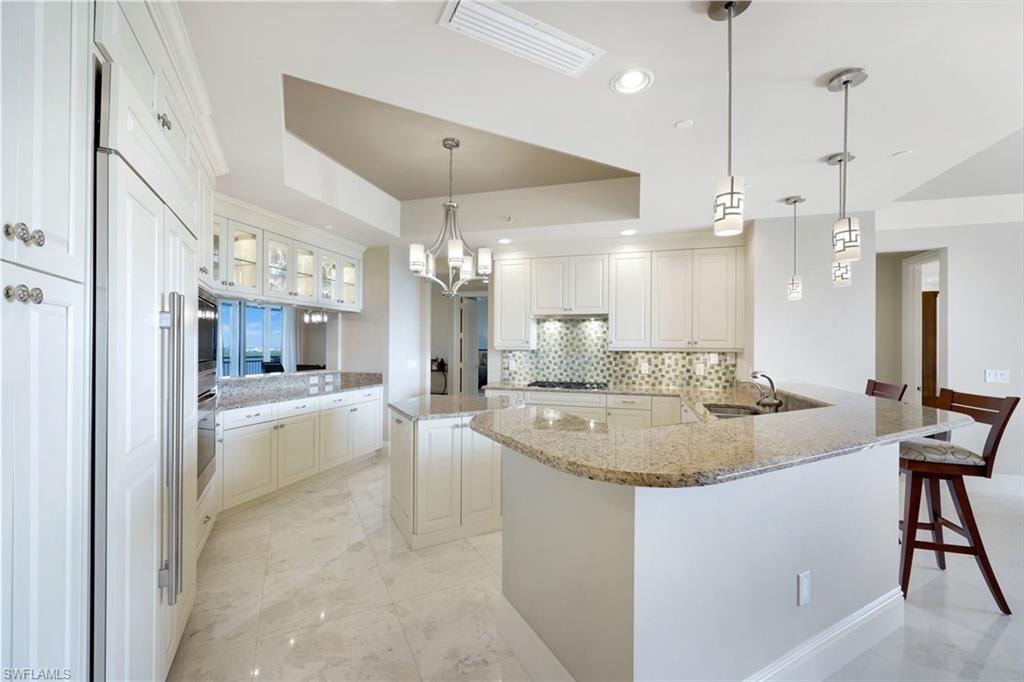 Kitchen featuring white cabinetry, light-colored tile flooring, granite countertops, and a mosaic tile backsplash
