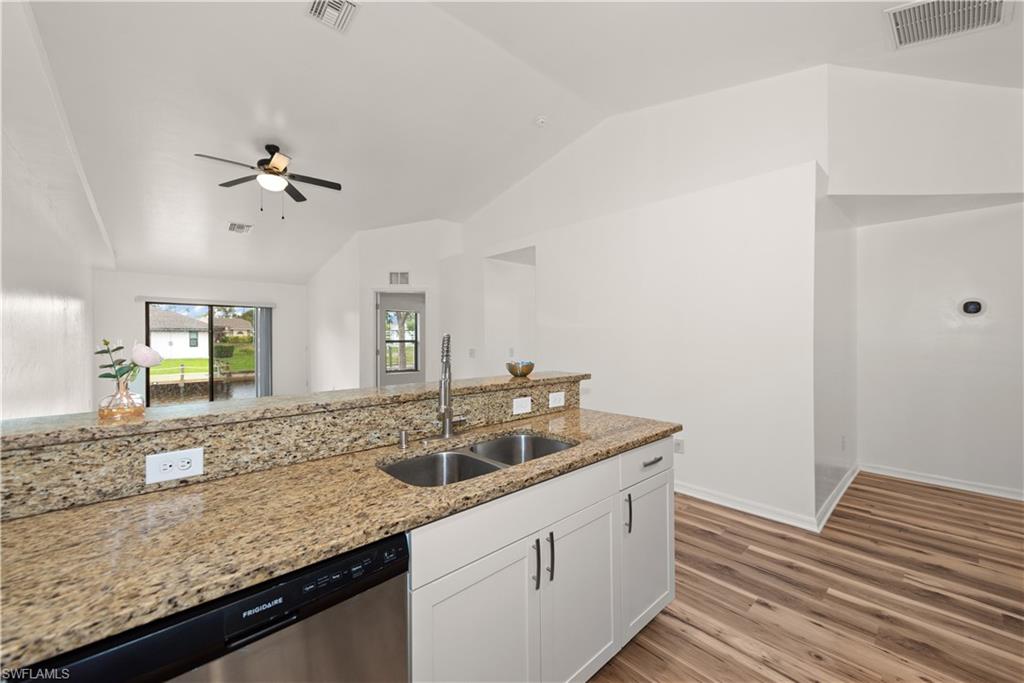 Kitchen bar with a stainless steel sink, light-toned cabinetry, and granite countertops