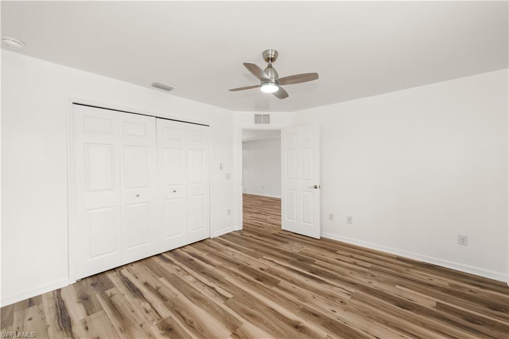 Wood-finish flooring, white walls, and a ceiling fan with integrated lighting