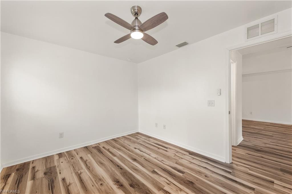 Wood-finish flooring, white walls, ceiling fan with integrated lighting, and a white door frame