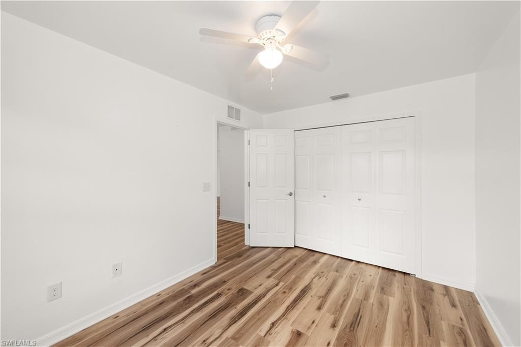 Wood-finish flooring, white walls, and a ceiling fan with integrated lighting