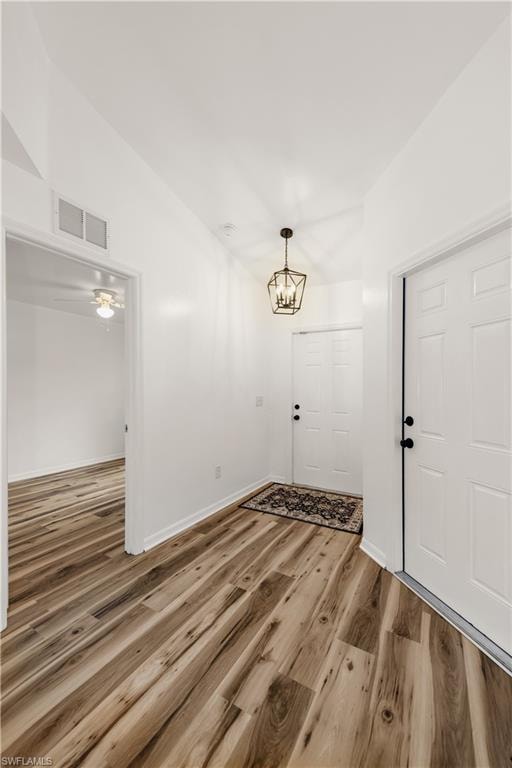 Light wood-finish flooring throughout, white interior walls, and a decorative black metal pendant light fixture