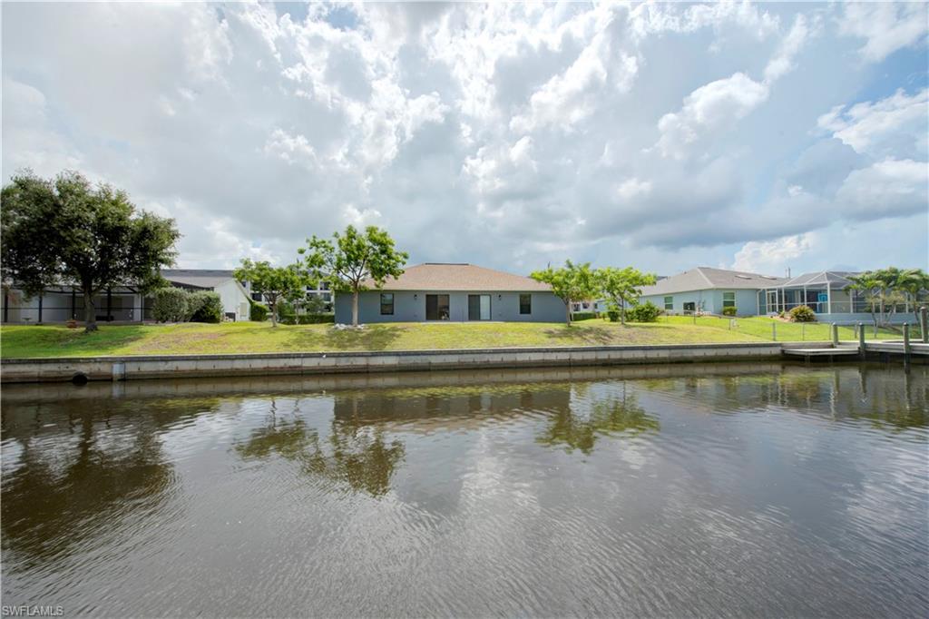 Waterfront property featuring a flat roofline, neutral exterior siding, and a wooden dock with pilings