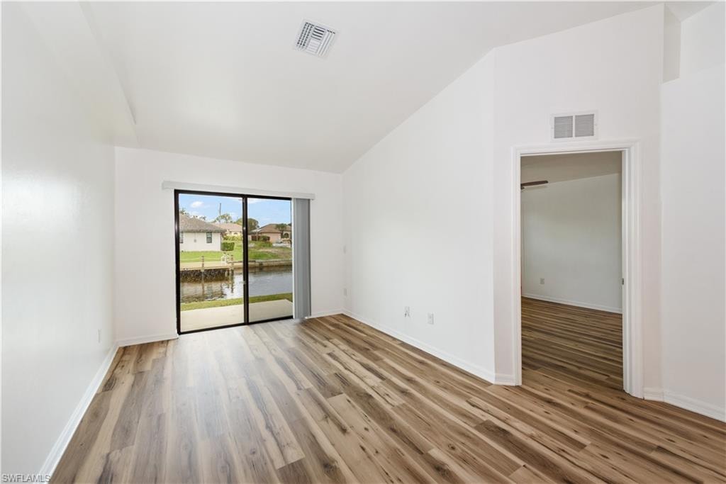 Wood-finish flooring, white walls, vaulted ceiling, sliding glass door, and canal access