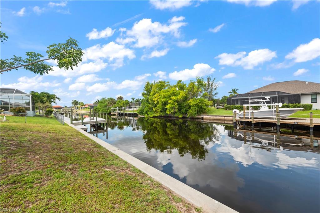 Waterfront property featuring a concrete seawall, expansive canal access, and a private dock with a boat lift