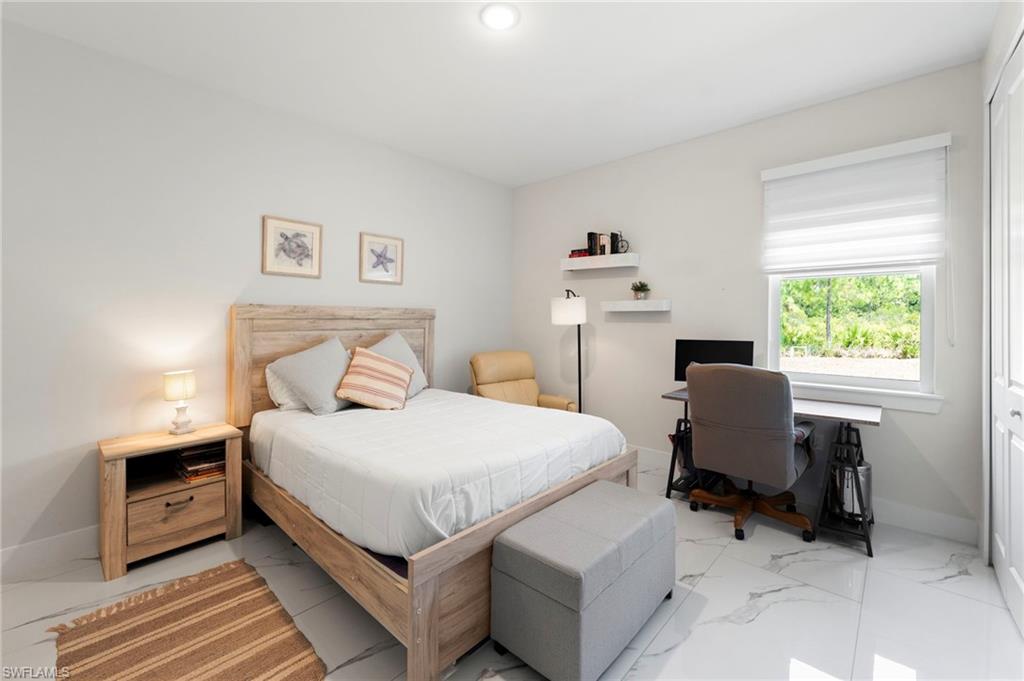 White marble-look flooring, light-toned walls, a window with a white blind, and a built-in closet with white doors