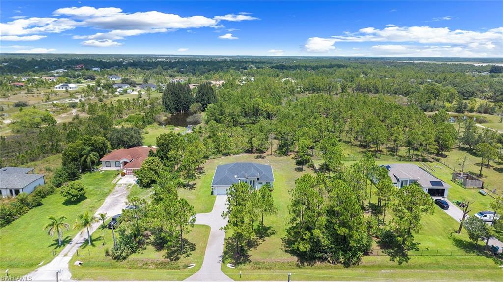Expansive rural property featuring mature landscaping with towering trees, manicured lawn, and multiple structures set across substantial acreage