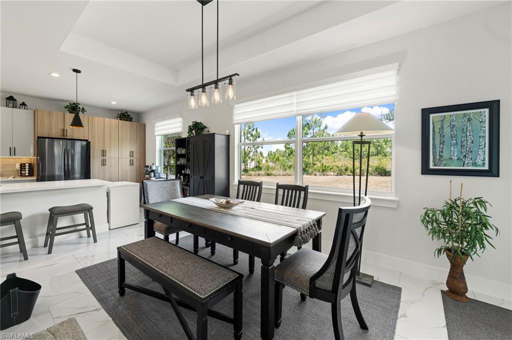 Open-concept living space with large windows, tray ceiling, recessed lighting, and white tile flooring