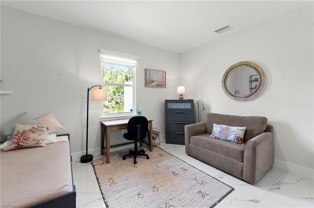Bright, light-filled bedroom featuring large windows with natural light, polished concrete flooring, and neutral white walls