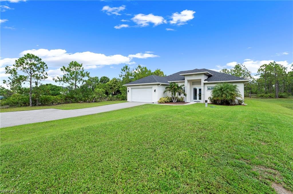 Spacious single-story residence with a modern architectural design, featuring a clean white exterior, attached two-car garage, and a sprawling manicured lawn bordered by mature native vegetation and tree lines