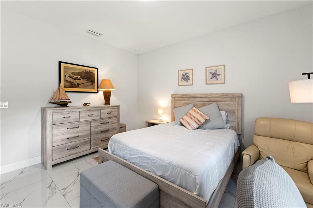 Serene primary bedroom showcasing a wood-finish bed frame with upholstered headboard, soft-blue bedding, and coordinating throw pillows