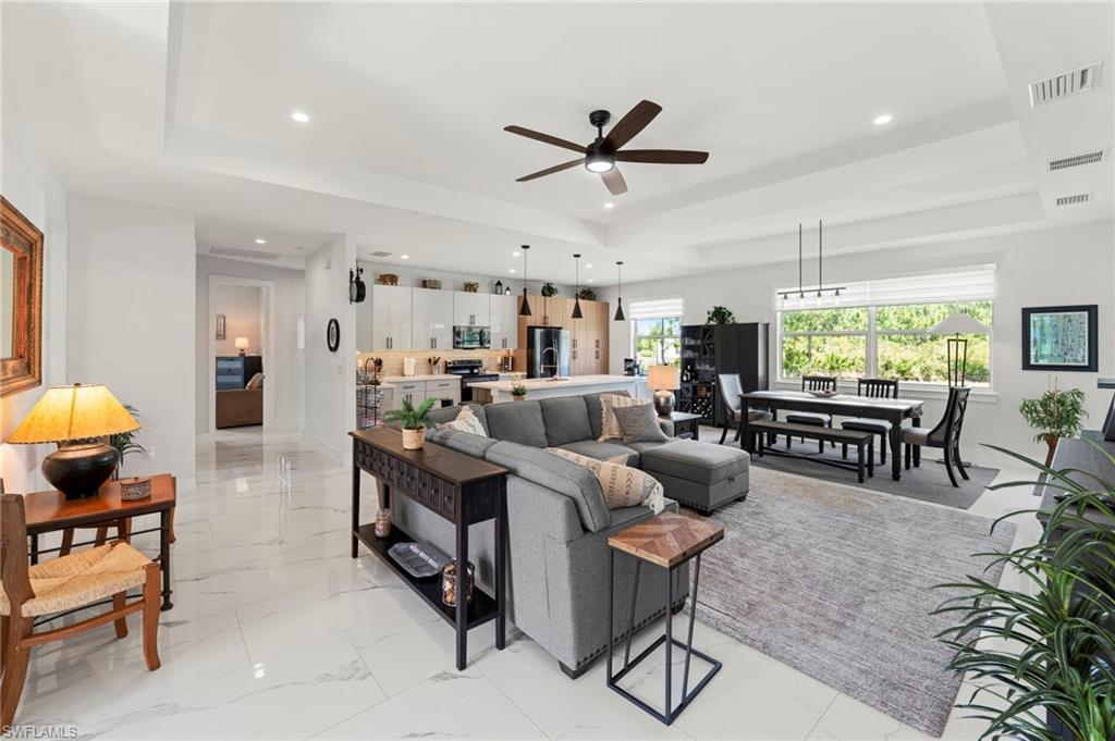 Open-concept living area featuring polished tile flooring, a ceiling fan with integrated lighting, and abundant natural light from multiple windows