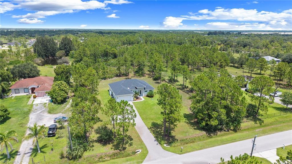Expansive property featuring a curved asphalt driveway, mature trees, and a surrounding natural landscape